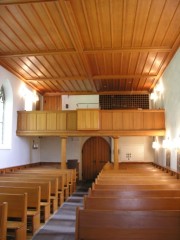 Vue intérieure en direction de la tribune de l'orgue dont les tuyaux sont masqués par la palissade en bois, à droite, en tribune. Cliché personnel